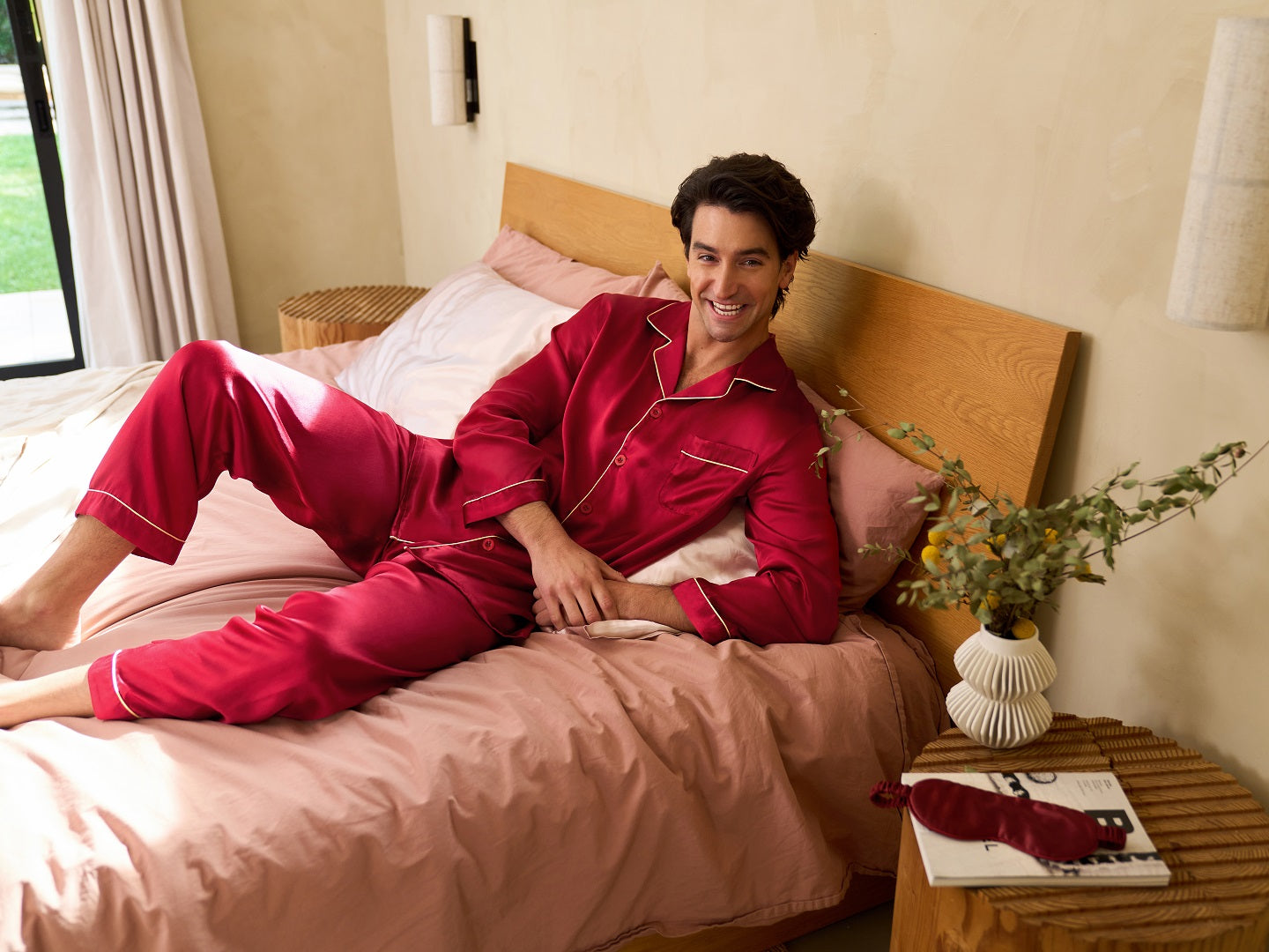 Man lying comfortably on a bed in a red long-sleeve silk pajama set, showcasing the natural warmth, elegance, and skincare benefits of silk pajamas for cozy winter nights.