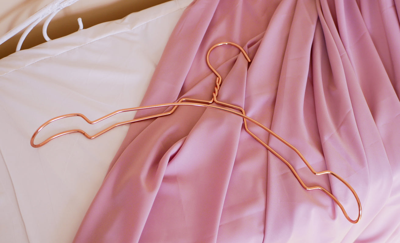 A silk nightgown laid flat on a bed with a hanger placed on top, illustrating proper care and storage techniques to keep it soft, fresh, and luxurious.