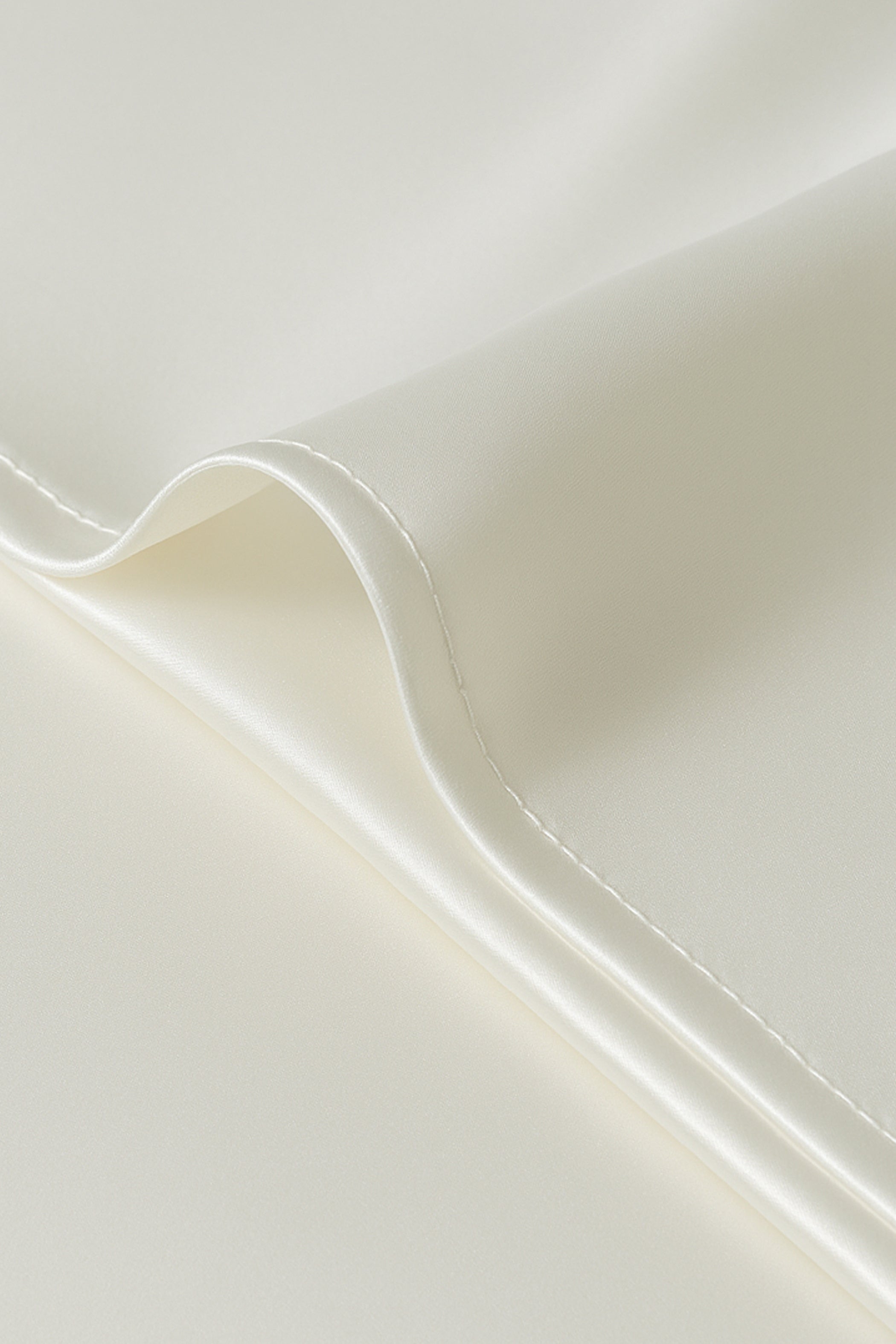 Model in white sleepwear holding a Jasmisilk 100% mulberry silk envelope pillowcase in ivory