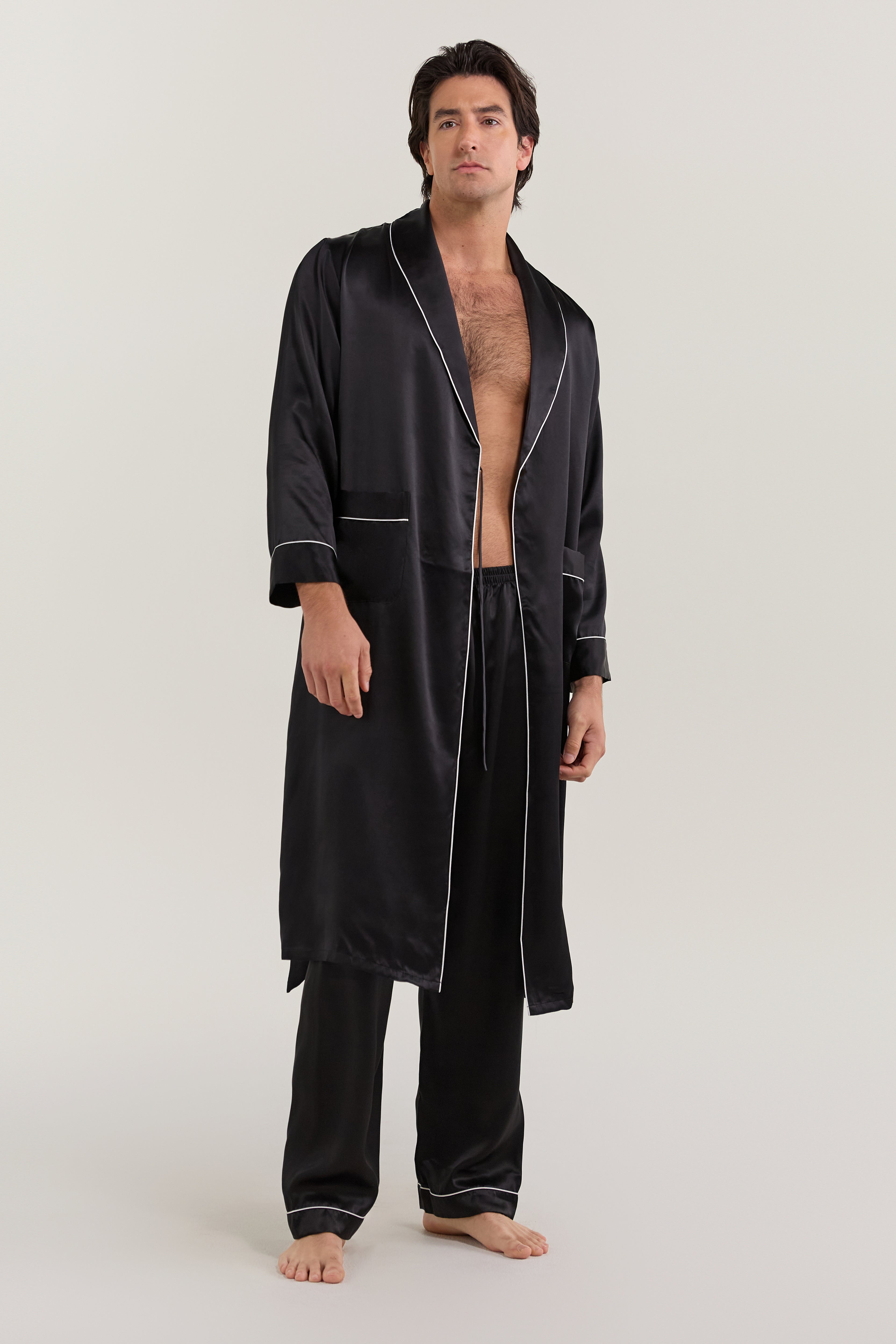Man wearing open-front Jasmisilk men's black pure silk robe with white piping, paired with matching silk pants