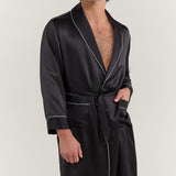 Close-up of man wearing Jasmisilk men's black pure silk robe with shawl collar, white piping, and waist tie