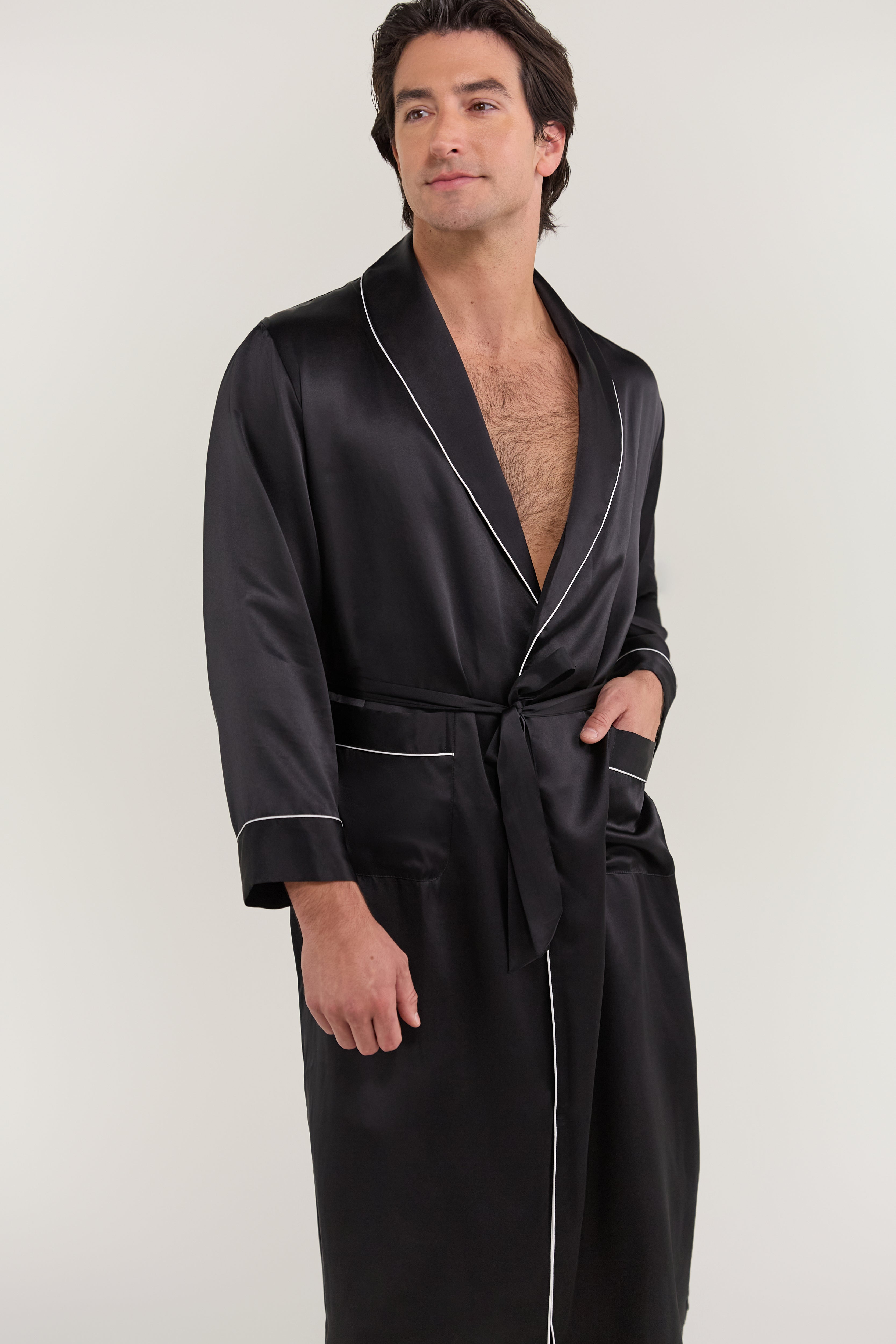 Close-up of man wearing Jasmisilk men's black pure silk robe with shawl collar, white piping, and waist tie