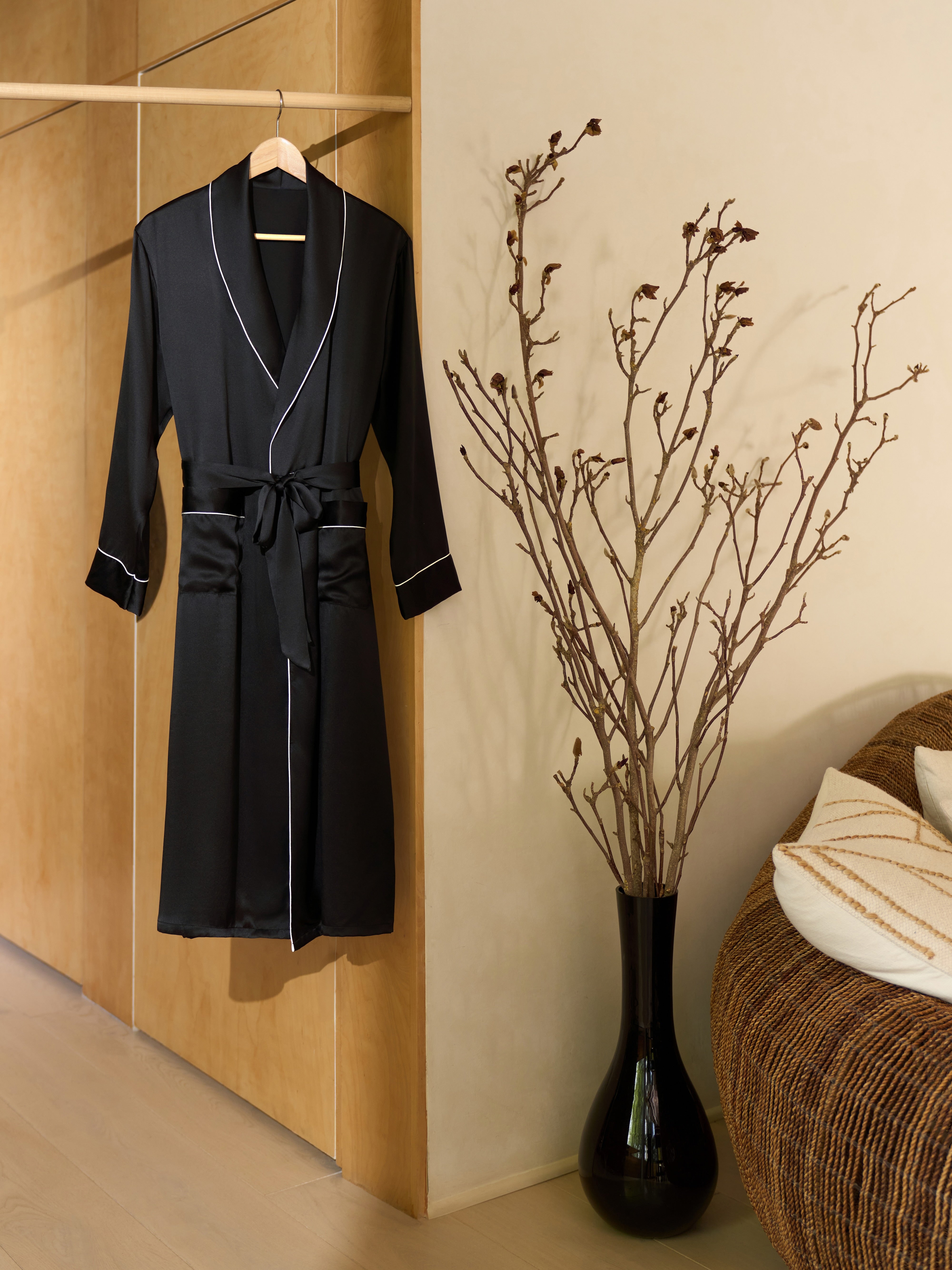 Jasmisilk men's black pure silk robe with white piping hanging on wooden hanger