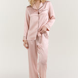 Woman wearing Jasmisilk pink silk long-sleeve pajama set with black piping