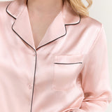 Close-up of women's pink silk pajama top with black piping and chest pocket from Jasmisilk