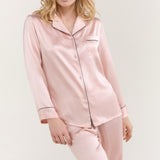 Model wearing Jasmisilk women's pink silk pajama set with black trim