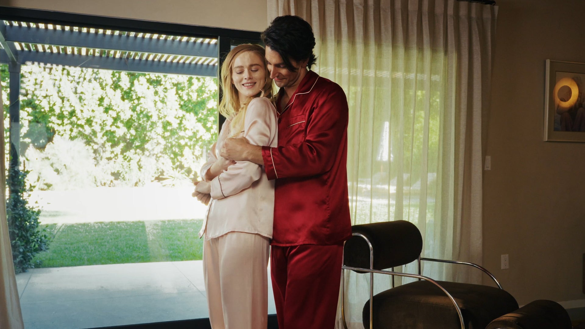 A couple in silk loungewear dancing together at home, sharing a romantic and intimate moment.