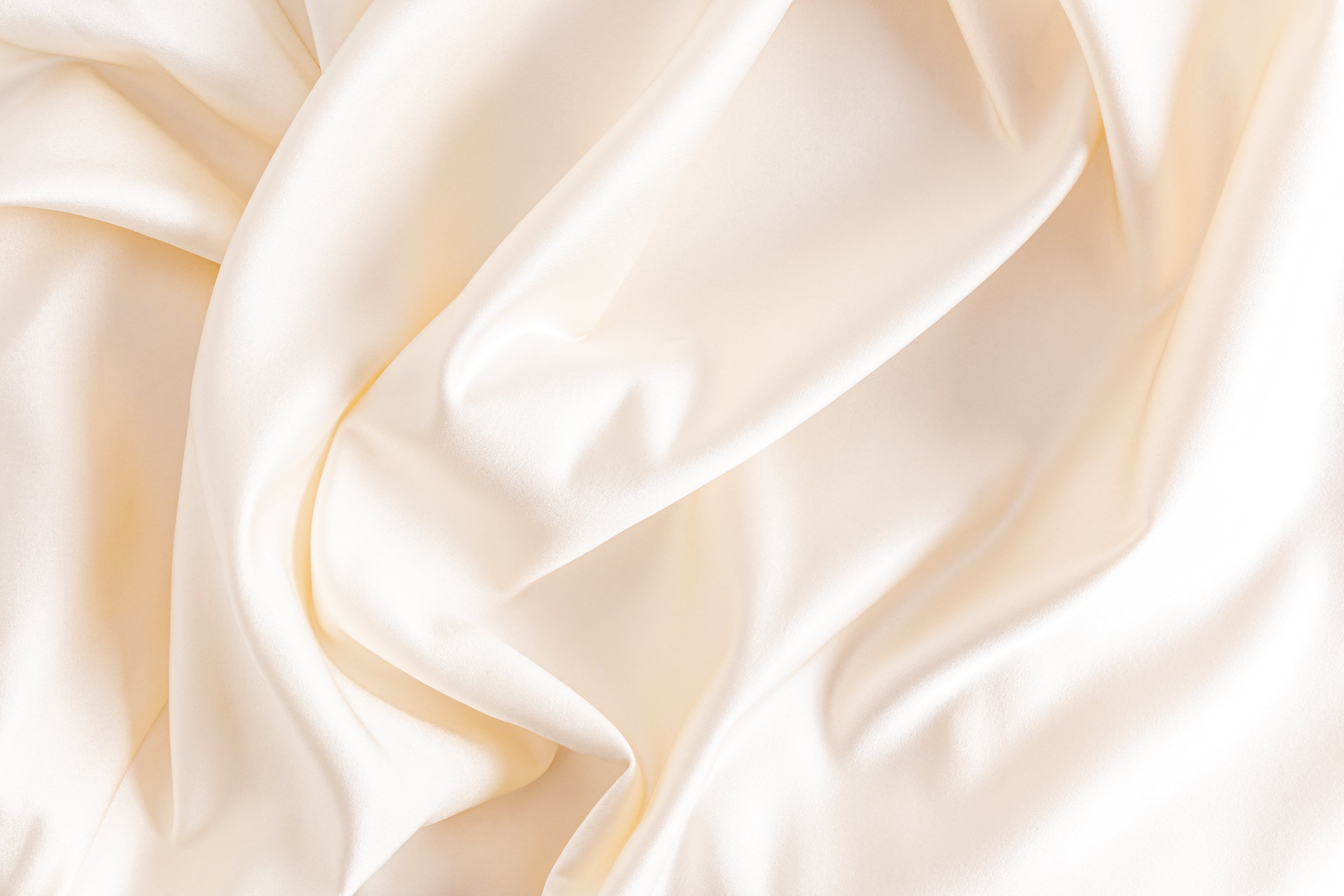Close-up of white silk fabric, highlighting its luxurious texture, natural sheen, and benefits for skin health and comfort.
