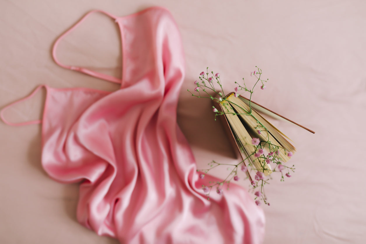 Silk nightgown elegantly laid on a book with flowers, showcasing Jasmisilk’s 100% Mulberry silk—soft, breathable, and luxurious.
