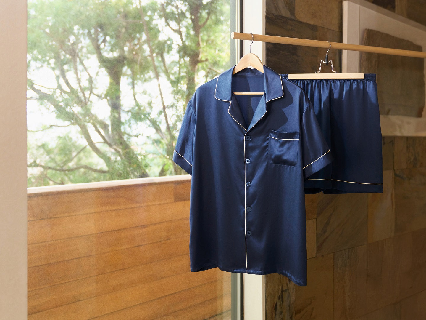 A set of luxury silk pajamas hanging neatly on a wooden hanger, showcasing smooth, glossy fabric.